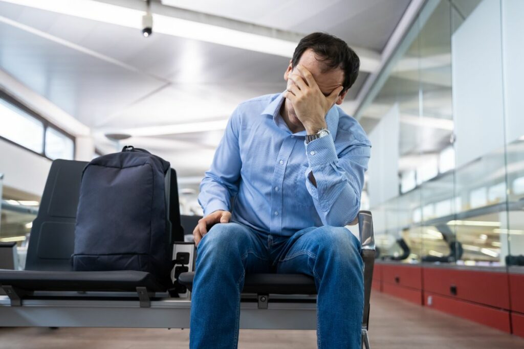 cancelamento de passagem aérea, homem sentado preocupado