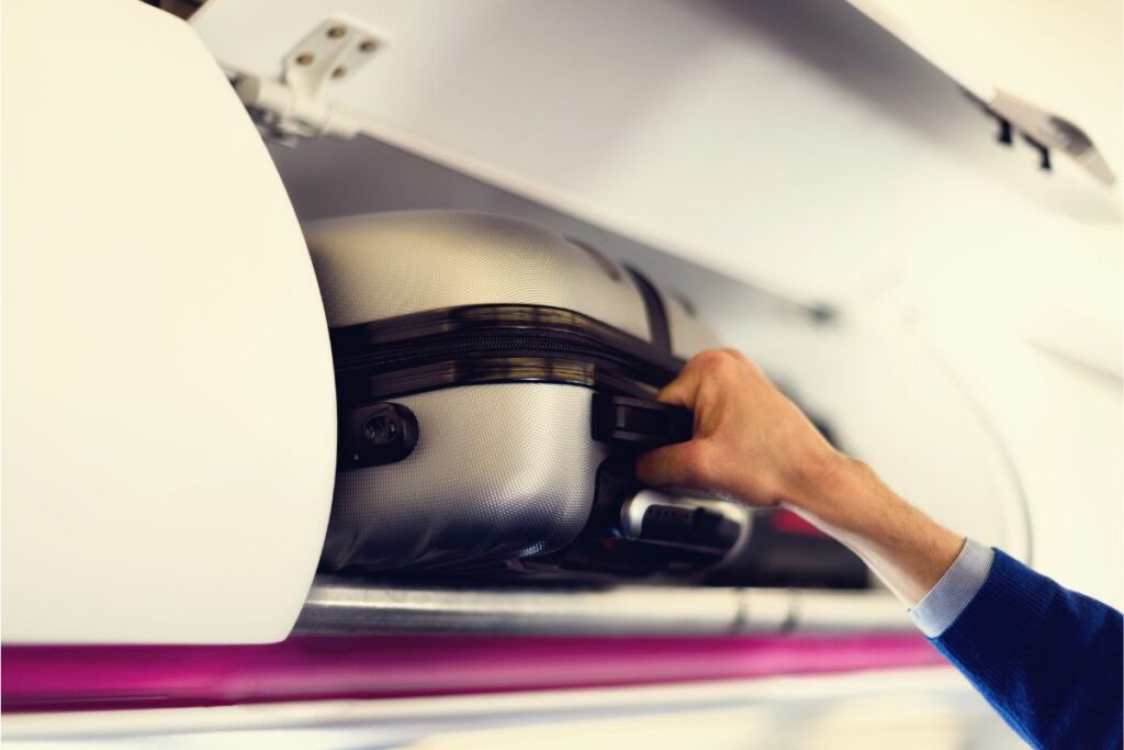 Homem recolhendo sua mala no bagageiro 