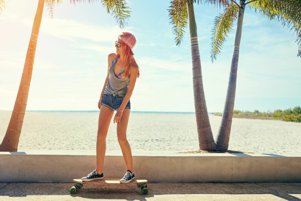 Menina andando de skate na calçada da praia